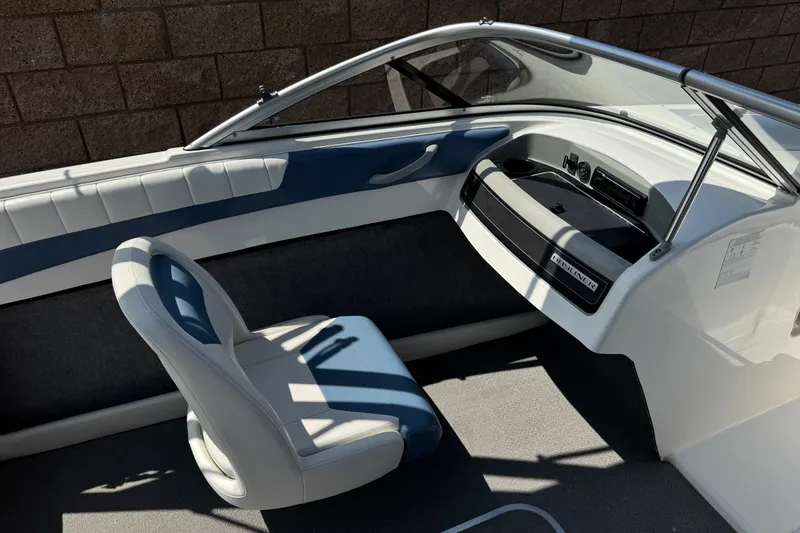 Slide: The Image of 2012 Bayliner 195 Bowrider interior with white and blue seating, dashboard, and windshield. - 20