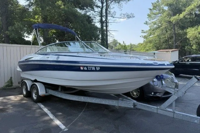 The Image of 2008 Crownline 200 LS boat on trailer in parking lot, surrounded by trees. - 0