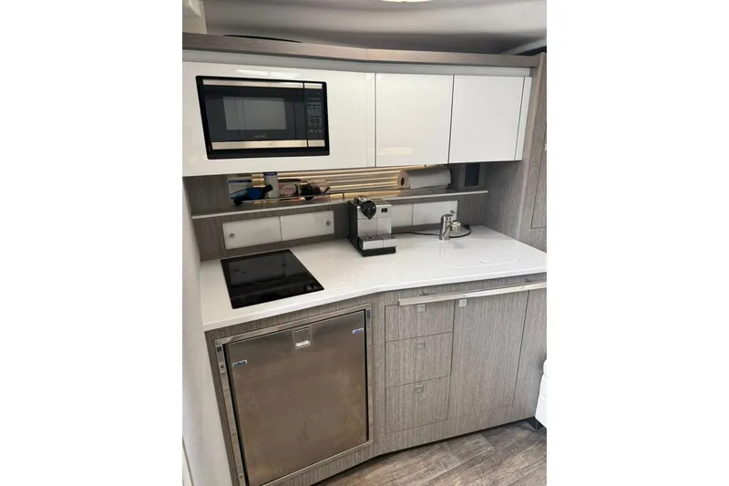Slide: The Image of Modern kitchenette in 2021 Monterey 355 Sport Yacht with microwave, stove, and sleek cabinetry. - 28