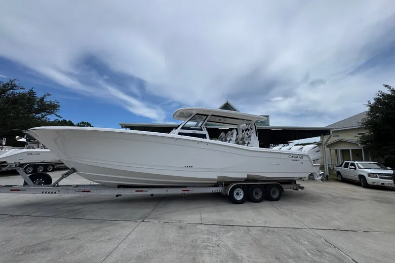 Slide: The Image of 2027 Caymas 401 DR boat on trailer, parked outdoors under cloudy sky. - 2