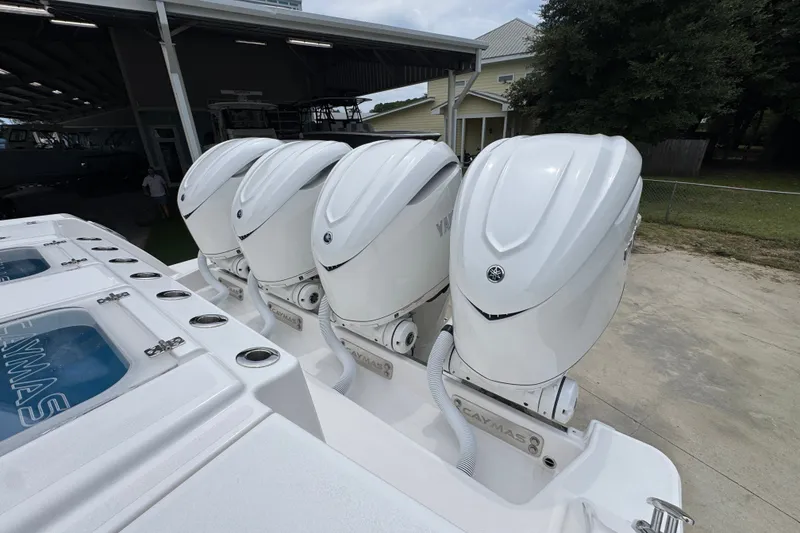 Slide: The Image of 2027 Caymas 401 DR boat with four powerful outboard engines, docked near a covered marina. - 55