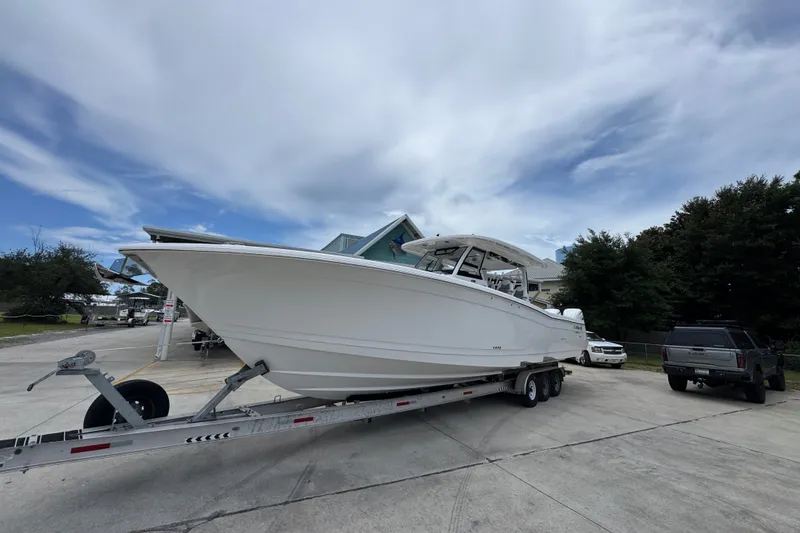 Slide: The Image of 2027 Caymas 401 DR boat on trailer, parked outdoors under a cloudy sky. - 4