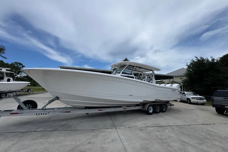 Slide: The Image of 2027 Caymas 401 DR boat on trailer, parked outdoors under a cloudy sky. - 3