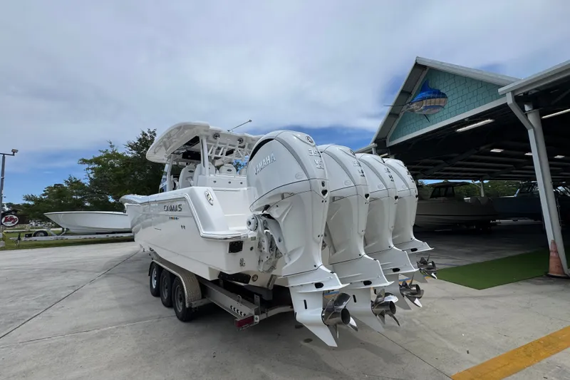 Slide: The Image of 2027 Caymas 401 DR boat with four powerful outboard engines, parked near a marina. - 18