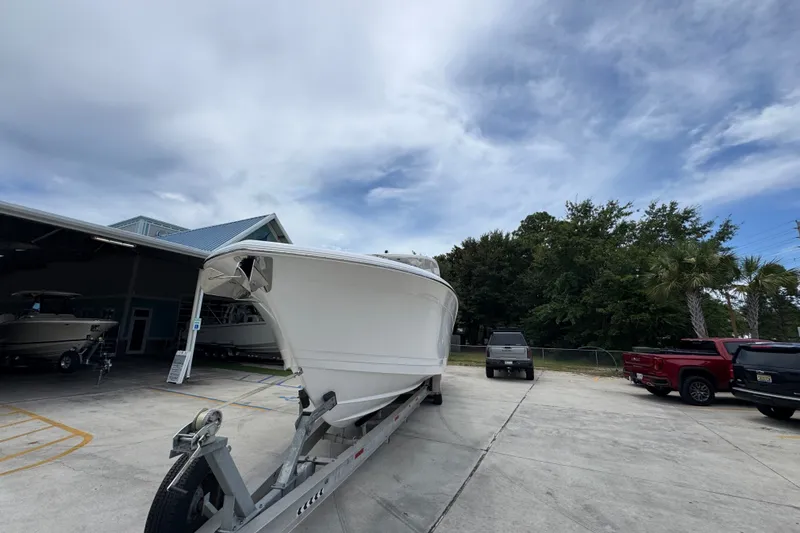 Slide: The Image of 2027 Caymas 401 DR boat on trailer, parked outdoors near vehicles and trees. - 6