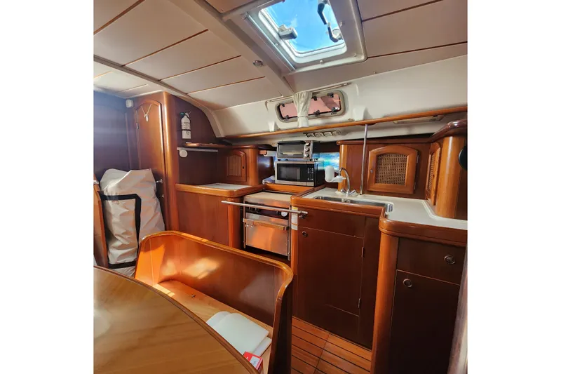 Slide: The Image of Interior of 1999 Beneteau Oceanis 411 Celebration yacht, featuring a wooden galley and dining area. - 23