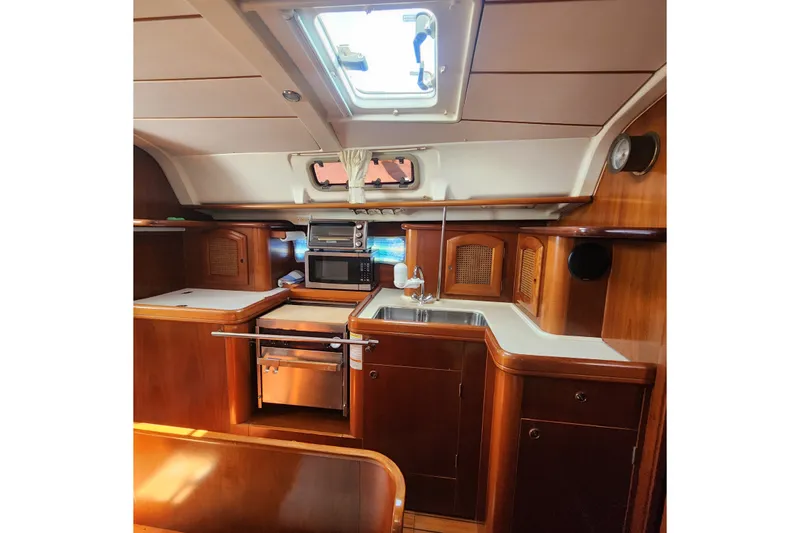 Slide: The Image of Interior of 1999 Beneteau Oceanis 411 Celebration yacht, featuring a well-equipped wooden galley kitchen. - 22