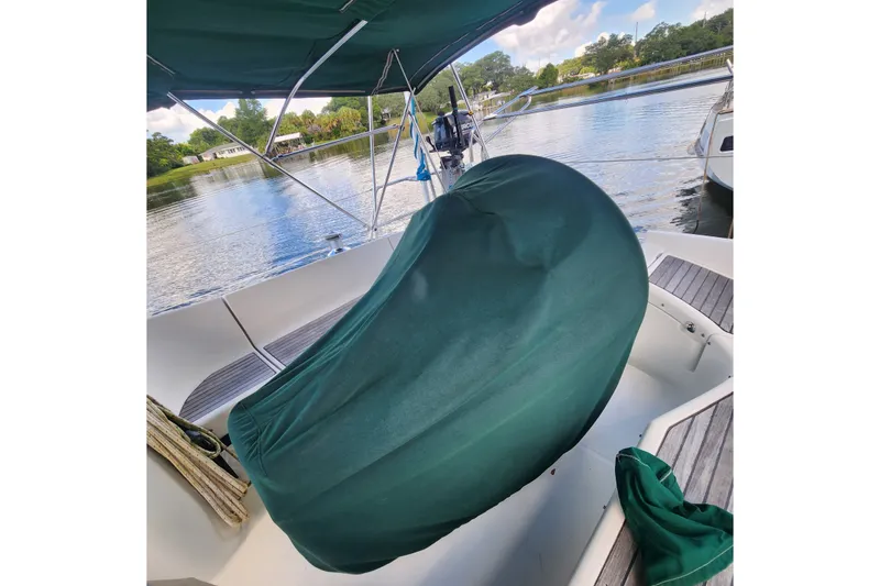 Slide: The Image of Beneteau Oceanis 411 Celebration 1999 sailboat cockpit with green cover, docked by a serene lake. - 7