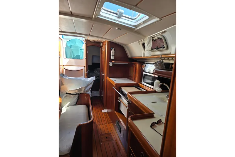 Slide: The Image of Interior of 1999 Beneteau Oceanis 411 Celebration yacht, featuring wooden cabinetry and compact kitchen. - 21