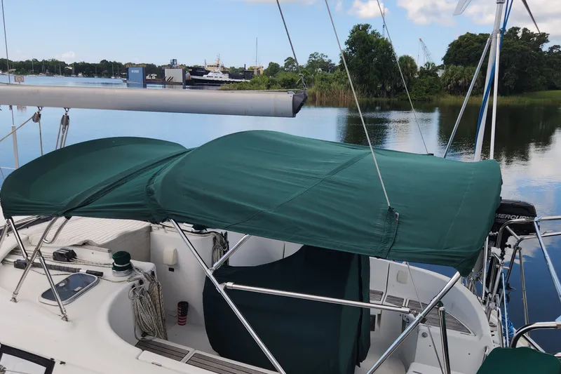 Slide: The Image of Beneteau Oceanis 411 Celebration sailboat with green canopy, docked on a calm lake. - 5