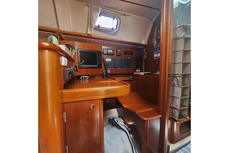 Slide: The Image of Navigation station inside 1999 Beneteau Oceanis 411 Celebration yacht, featuring wood finish and electronics. - 19