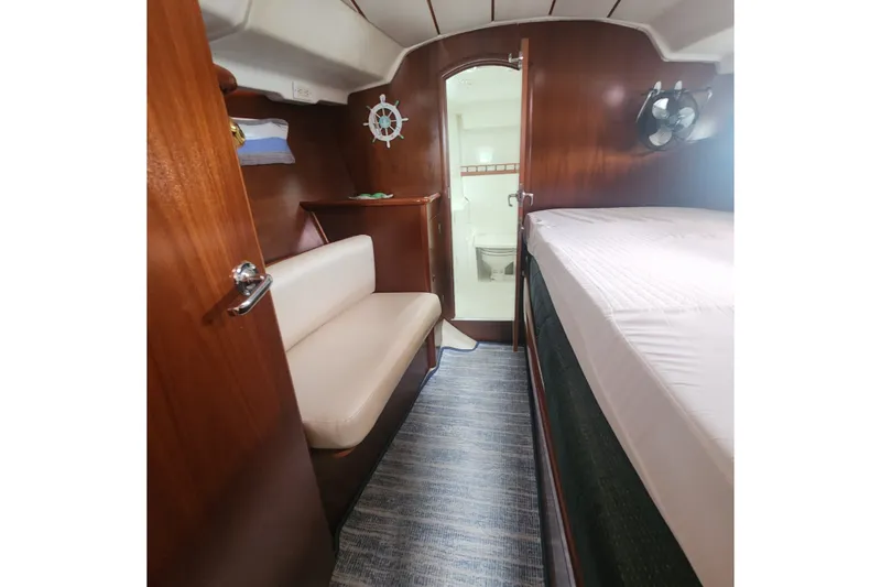 Slide: The Image of Interior cabin of 1999 Beneteau Oceanis 411 Celebration yacht, featuring wood paneling and cozy seating. - 28