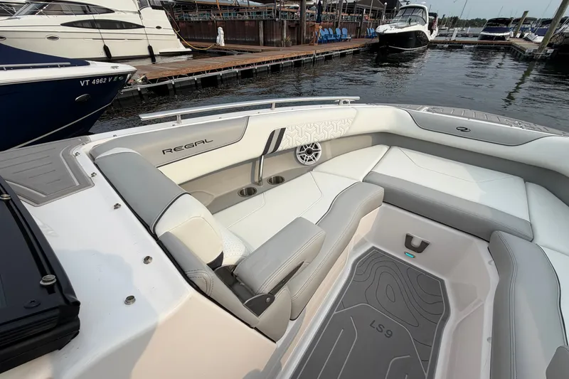Slide: The Image of 2024 Regal LS9 boat interior with sleek seating and modern design at a marina. - 33