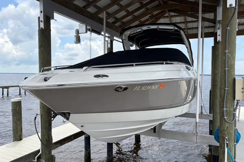 The Image of 2007 Chaparral 256 SSi boat docked under a covered structure by the water. - 1