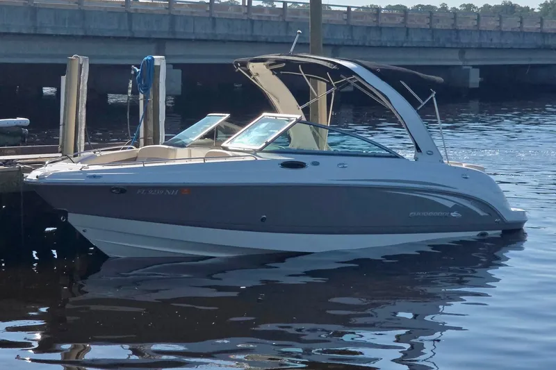 Slide: The Image of 2007 Chaparral 256 SSi boat docked on calm water near a bridge. - 22