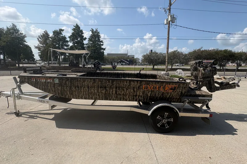 Slide: The Image of 2026 Excel 1751 Shallow Water F4 boat on trailer, camo design, parked outdoors. - 8