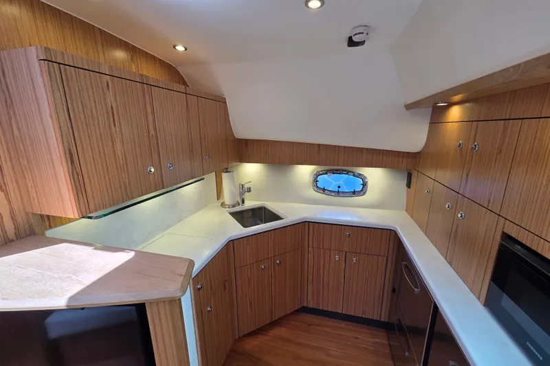Slide: The Image of 2023 Tiara Yachts 4300 Open interior kitchen with wood cabinetry and modern appliances. - 19