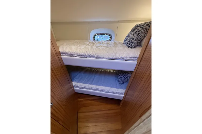 Slide: The Image of Bunk beds in 2023 Tiara Yachts 4300 Open cabin, featuring wooden interior and porthole. - 28