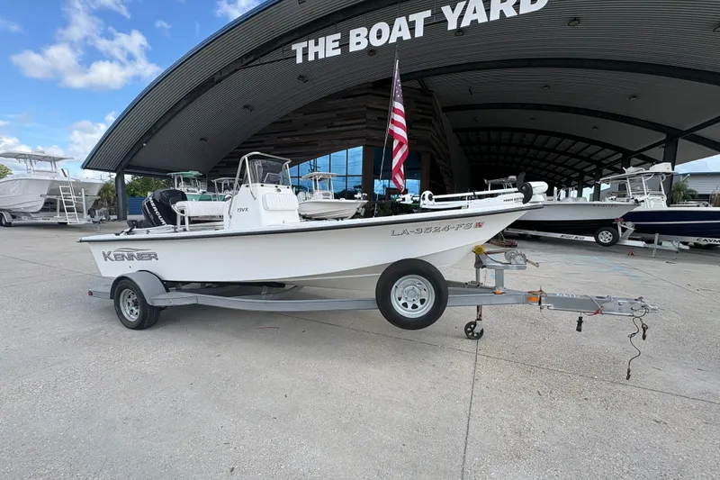 Slide: The Image of 2008 Kenner 19 VX boat on trailer at The Boat Yard, featuring American flag. - 2