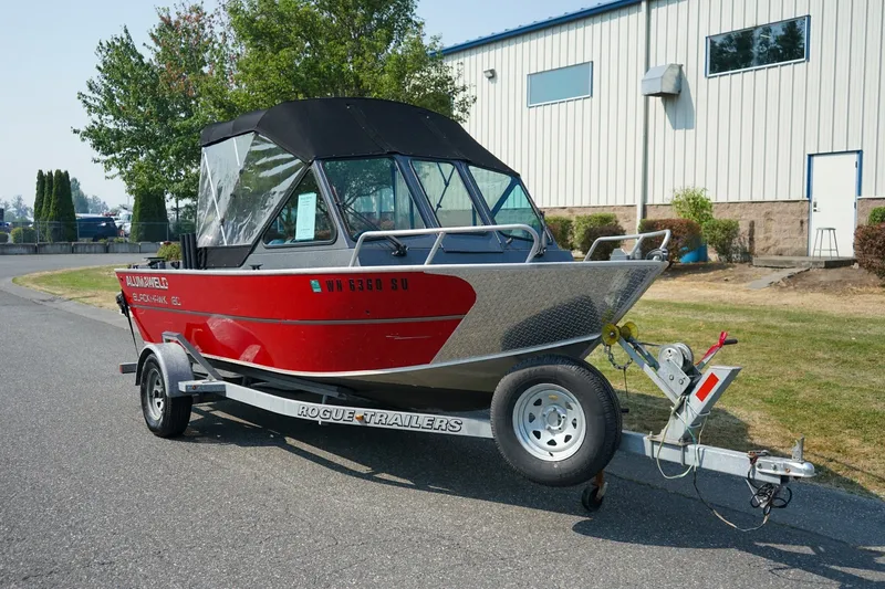 The Image of 2020 Alumaweld Blackhawk 180 boat on trailer, parked outdoors near industrial building. - 1