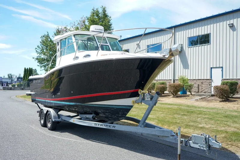 The Image of 2019 Striper 270 Walkaround boat on trailer, parked near industrial building. - 1