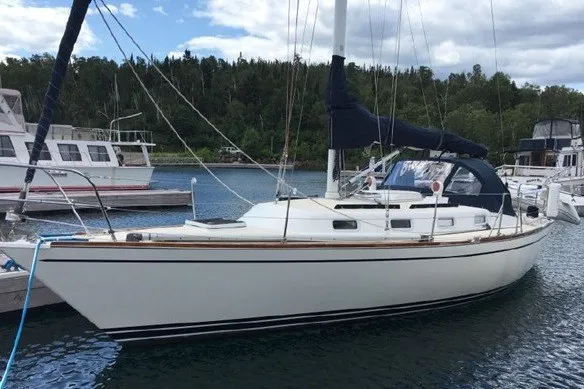 The Image of 1987 Tartan 34-2 sailboat docked in a marina with forested background. - 0