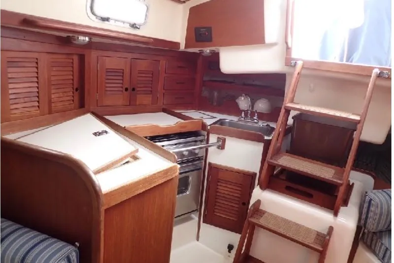 Slide: The Image of 1987 Tartan 34-2 yacht interior with wooden cabinetry and compact kitchen area. - 5