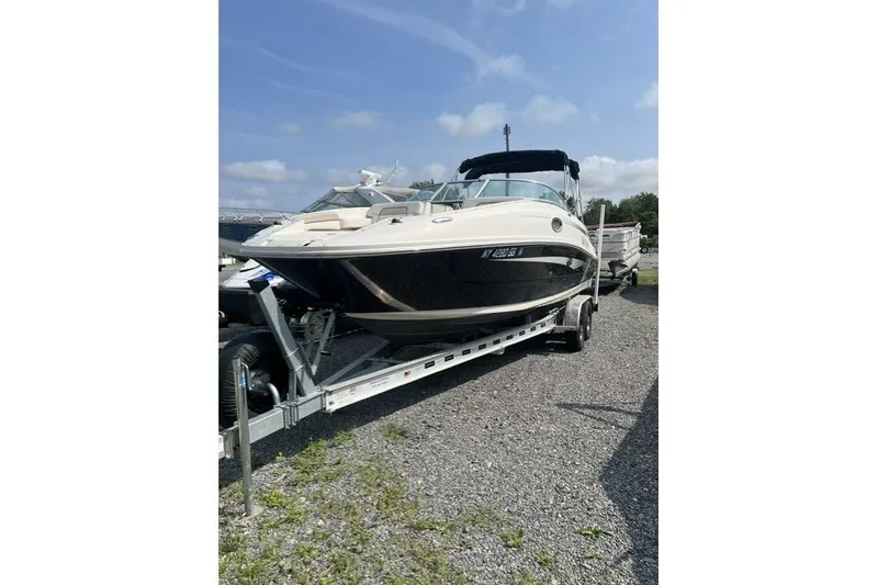 The Image of 2010 Sea Ray 260 Sundeck boat on trailer, parked outdoors under blue sky. - 0