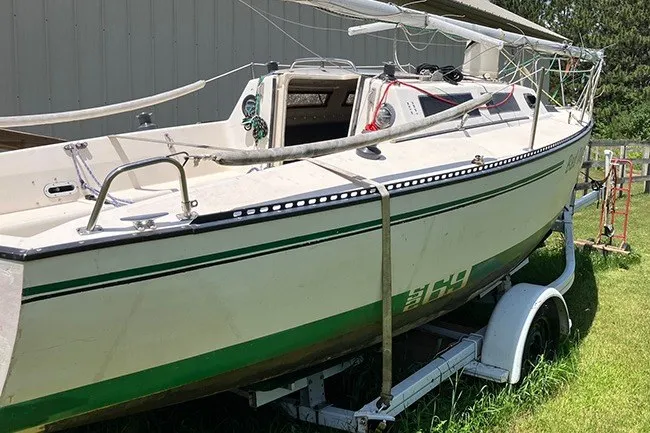 Slide: The Image of 1984 S2 6.9 sailboat on trailer, white with green accents, parked on grass. - 5