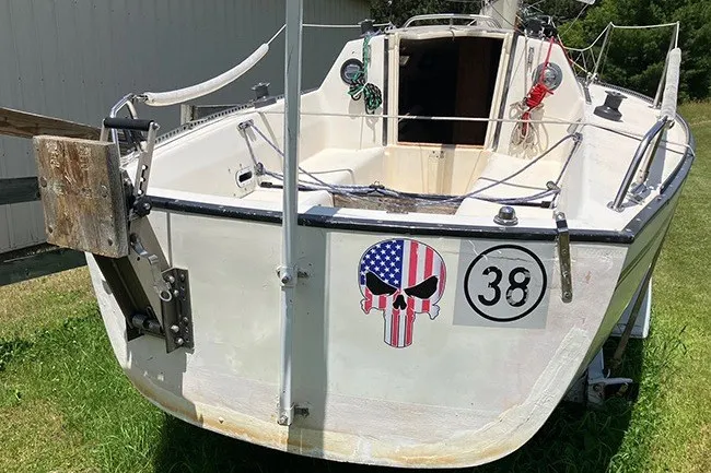 Slide: The Image of 1984 S2 6.9 sailboat with skull decal and number 38 on grassy area. - 6