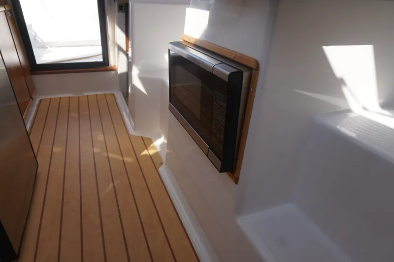 Slide: The Image of Interior of a 2018 Cutwater C-24 boat featuring a microwave and wooden flooring. - 29