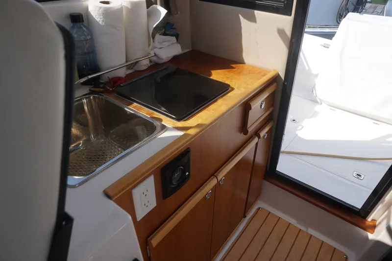Slide: The Image of 2018 Cutwater C-24 boat interior with kitchenette, sink, and wooden cabinetry. - 32