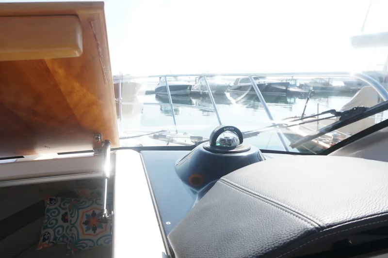 Slide: The Image of Interior view of 2018 Cutwater C-24 boat cockpit with compass and marina background. - 26