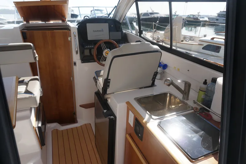 Slide: The Image of Interior of a 2018 Cutwater C-24 boat featuring helm, sink, and wooden cabinetry. - 37