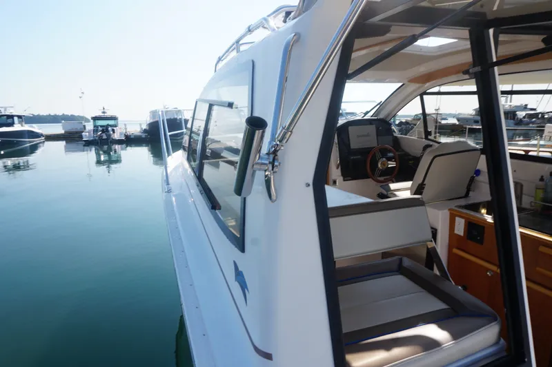 Slide: The Image of 2018 Cutwater C-24 boat interior view at marina, showcasing helm and seating area. - 36