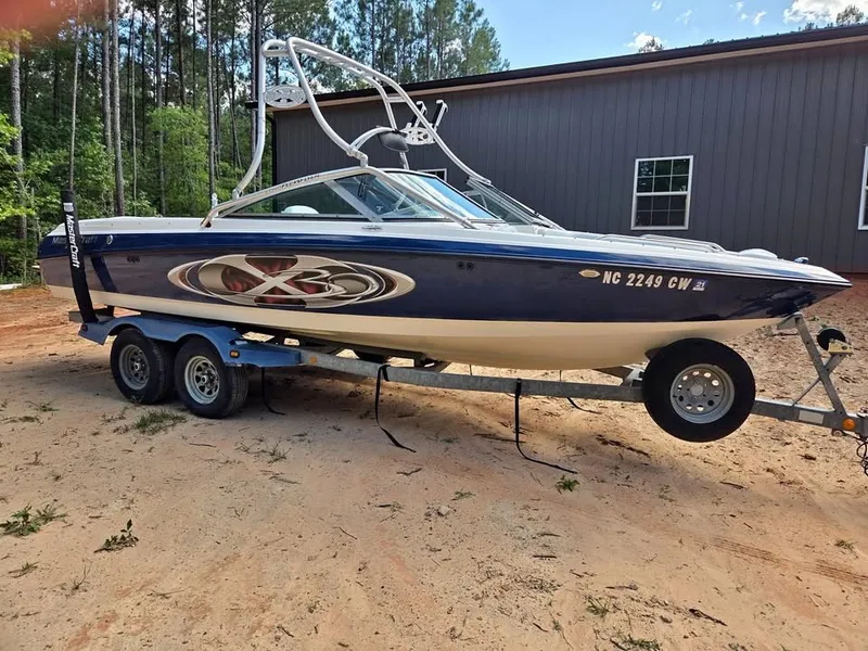 Slide: The Image of A blue and white 2003 MasterCraft X-30 boat on a trailer in front of a building. - 0