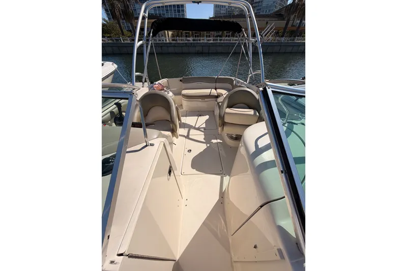 Slide: The Image of 2005 Sea Ray 240 Sundeck interior with seating, docked by the water. - 22