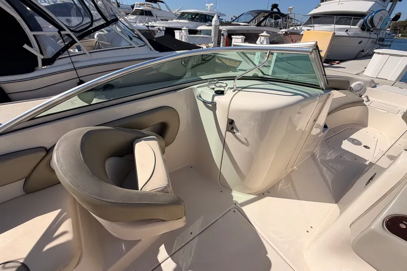 Slide: The Image of 2005 Sea Ray 240 Sundeck interior with seating and helm, docked among other boats. - 13