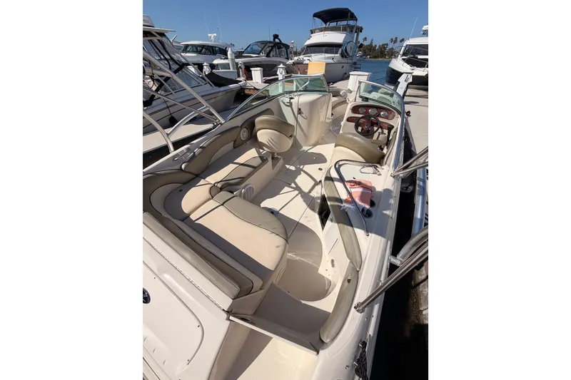 Slide: The Image of 2005 Sea Ray 240 Sundeck boat interior with seating and dashboard, docked among other boats. - 10