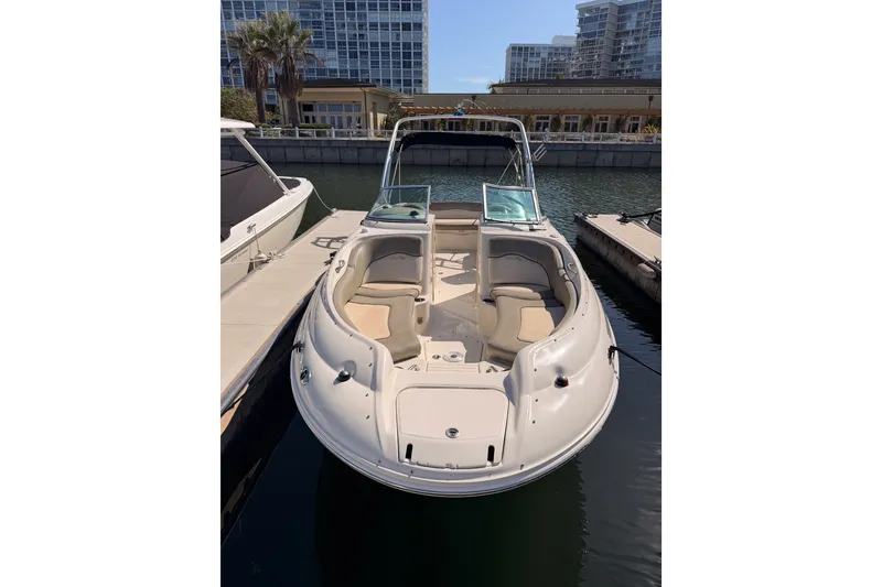 Slide: The Image of 2005 Sea Ray 240 Sundeck boat docked in a marina, featuring spacious seating. - 2