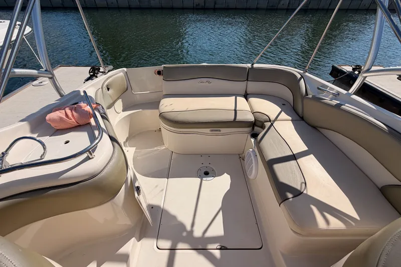 Slide: The Image of 2005 Sea Ray 240 Sundeck interior with beige seating, docked by the water. - 24