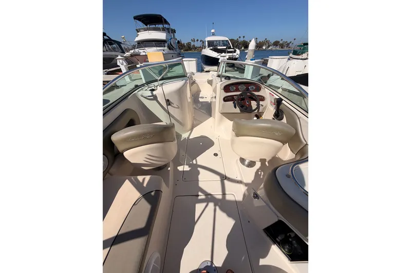 Slide: The Image of 2005 Sea Ray 240 Sundeck interior with helm, seating, and dashboard in a marina setting. - 11