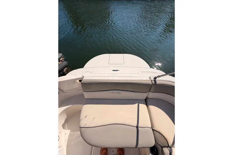 Slide: The Image of 2005 Sea Ray 240 Sundeck boat interior with beige seating, docked on calm water. - 37