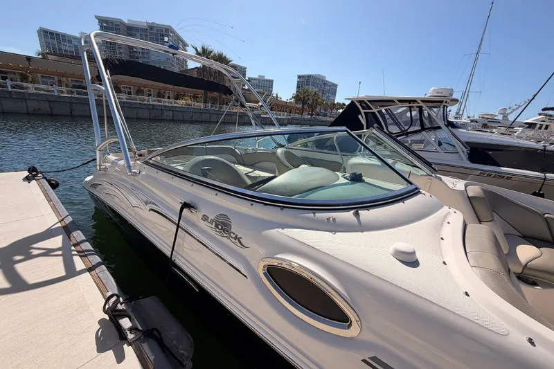 Slide: The Image of 2005 Sea Ray 240 Sundeck boat docked at marina, sunny day, modern buildings in background. - 4