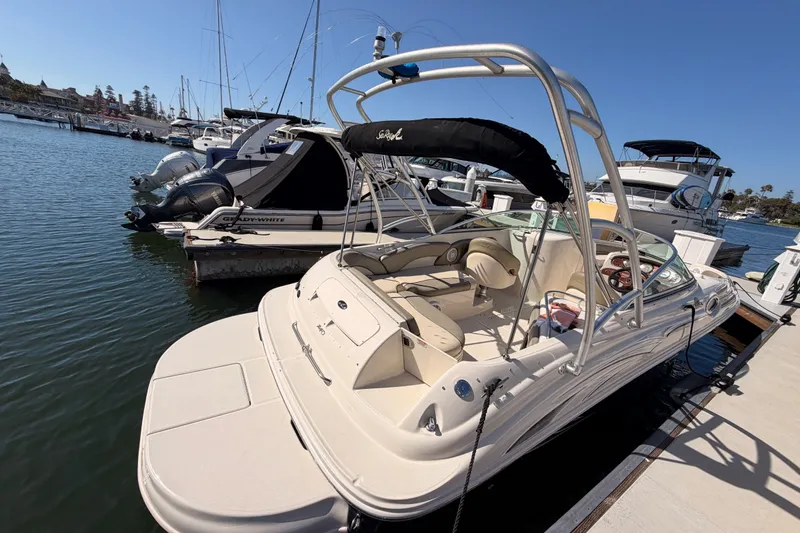 Slide: The Image of 2005 Sea Ray 240 Sundeck boat docked in a marina under clear blue skies. - 6