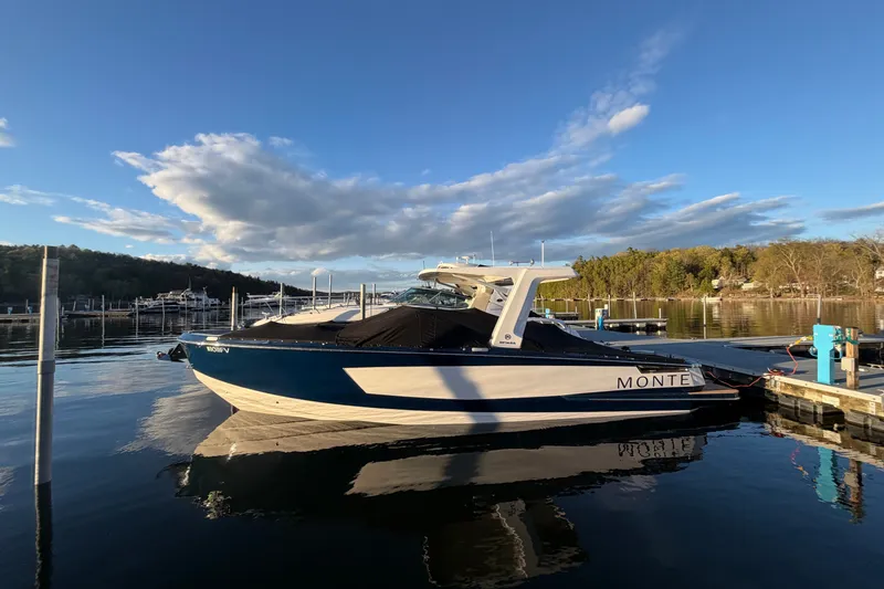 Slide: The Image of 2024 Aviara AV32 I/O boat docked on a serene lake under a blue sky. - 1