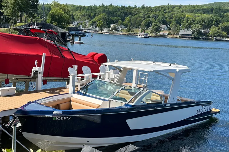 The Image of 2024 Aviara AV32 I/O boat docked on a serene lake with lush greenery. - 0