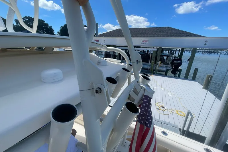 Slide: The Image of 2018 Grady-White Canyon 306 boat docked, featuring rod holders and an American flag. - 31