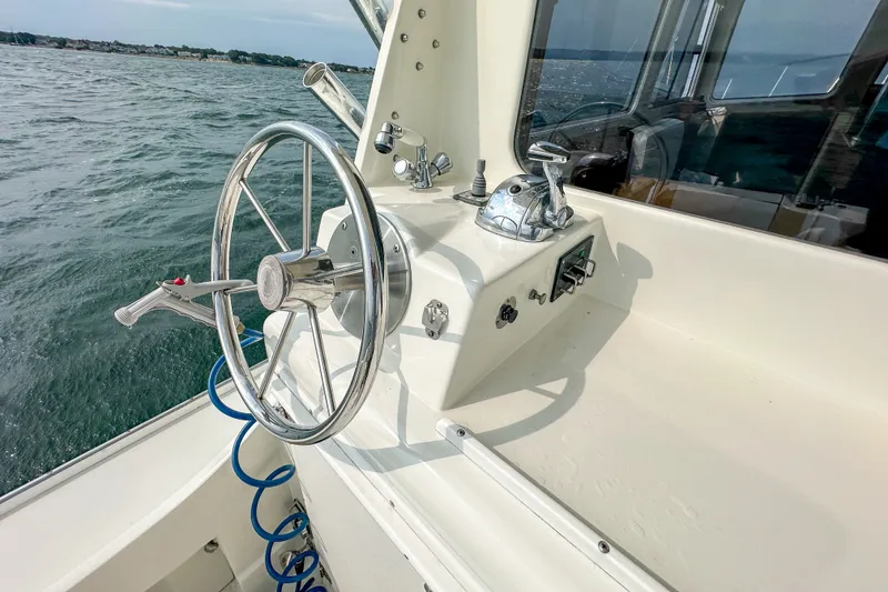 Slide: The Image of Steering wheel and controls of a 2003 Northern Bay 36 boat on the water. - 24