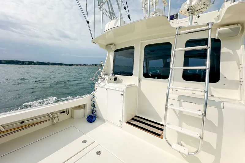 Slide: The Image of 2003 Northern Bay 36 boat deck with ladder, overlooking calm waters. - 18